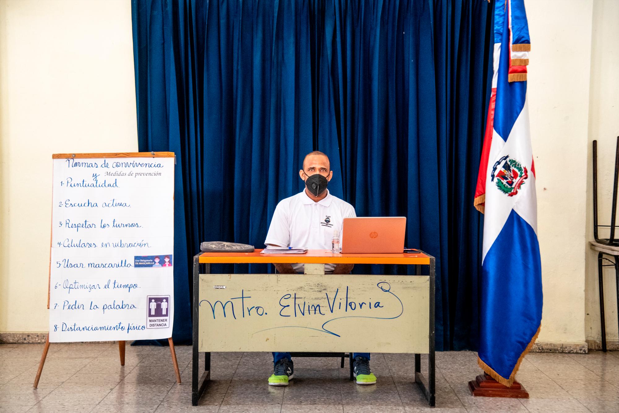 Desde un escritorio ubicado en el Salón de Actos de la escuela, Elvin Viloria imparte clases virtuales de Educación Física a sus alumnos.