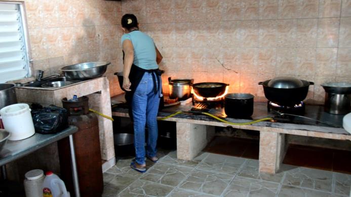 Una señora cocina los alimentos que se servirán en un liceo de Luperón
