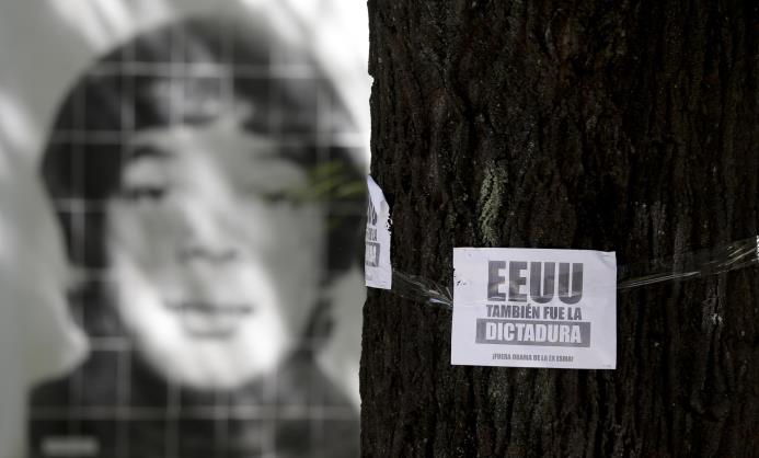 Una imagen de una persona desaparecida durante la última dictadura militar se ve detrás de un folleto sobre un árbol en el que se lee