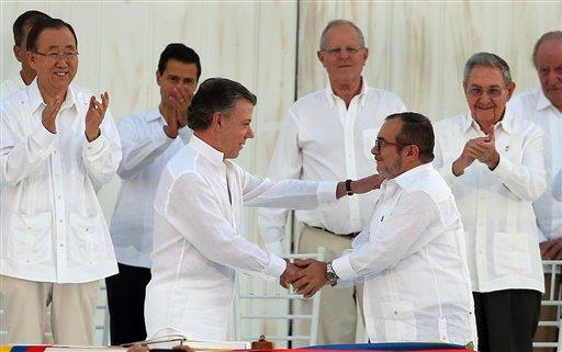 El presidente de Colombia, Juan Manuel Santos, a la izquierda, y el máximo comandante de las Fuerzas Armadas Revolucionarias de Colombia, Rodrigo Londoño, alias “Timochenko”, se dan la mano tras la firma del acuerdo de paz.