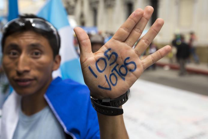 Un manifestante muestra una consigna escrita en su mano _ “105 votos” en referencia a los apoyos necesarios para que legisladores retiren la inmunidad al presidente de Guatemala, Otto Pérez Molina, para que pueda ser investigado _ durante una concentración en el exterior del Parlamento, en la ciudad de Guatemala el 1 de septiembre de 2015.
