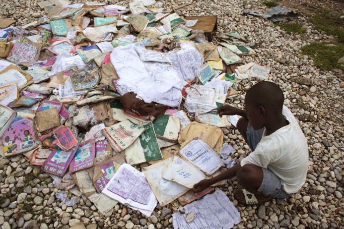 Rosmond Eliscar, 10 años, mira un grupo de libros mojados en Haití.