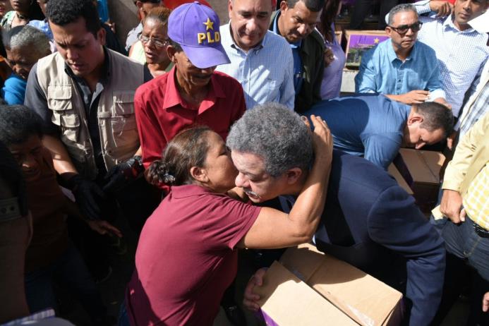 Una señora le susurra algo al oído al presidente del PLD, Leonel Fernández, durante la entrega de cajas con productos alimentos en Montecristi