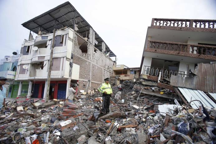 Un policía camina el domingo 17 de abril de 2016 sobre los escombros de construcciones destruidas por el terremoto en Pedernales, Ecuador. 