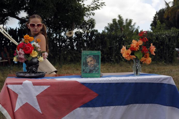 Una niña pasa junto a un pequeño altar en honor al fallecido líder cubano Fidel Castro instalado a la orilla de la carretera al paso de la caravana con las cenizas de Castro por la ciudad de Cruces, Cuba, el miércoles 30 de noviembre de 2016.