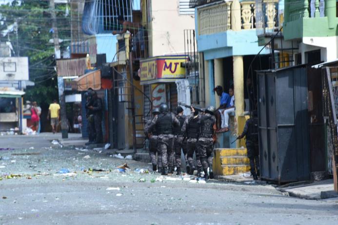 Agentes policiales disparan durante las protestas que realizan este viernes, 9 de septiembre de 2016, residentes en Capotillo tras la muerte de un hombre a manos de miembros de la DNCD.