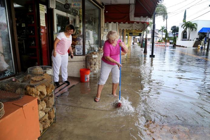 Kelly Spiliotis , izquierda, y Yiota Czeck trabajan en evitar inundaciones en la tienda de regalos Ambrosia en Tarpon Springs, Florida, el lunes 6 de junio de 2016