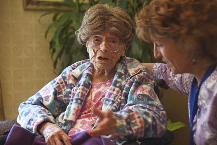 Fotografía de archivo de Adele Dunlap, entonces de 113 años, conversando con Susan Dempster, directora de actividades del Centro de Cuidados Country Arch.