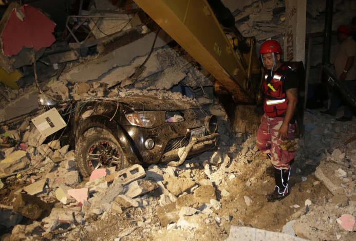 Un rescatista busca en los escombros de una casa destruida en Pedernales. 