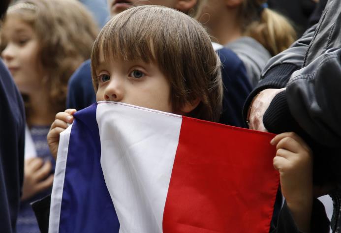 Un niño sostiene la bandera francesa durante una vigilia en solidaridad con Francia tras los atentados letales en París, frente a la embajada francesa en Bogotá, Colombia, el sábado 14 de noviembre de 2015. 