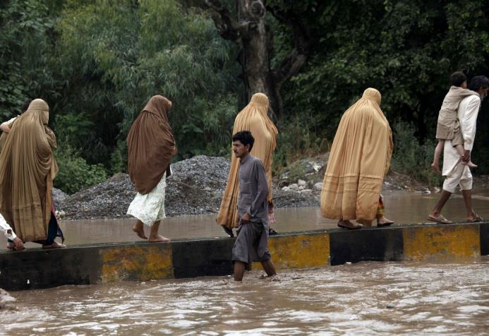 Varias personas caminan por las calles anegadas tras las intensas lluvias del monzón en la localidad de Charsadda, en la provincia de Khyber Pakhtunkhwa, Pakistán hoy 23 julio de 2015. 