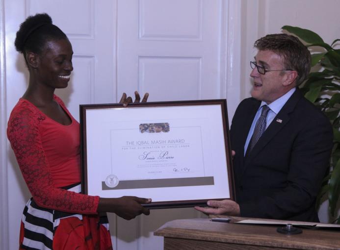 El embajador de Estados Unidos en el país entrega el reconocimiento a Solange Pierre, hija de la activista Sonia Pierre.