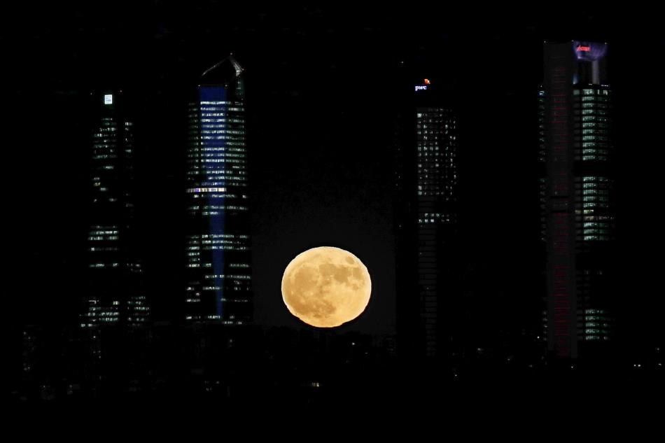 Vista de la luna junto a las cuatro torres del complejo empresarial “Cuatro Torres Business area” de Madrid.