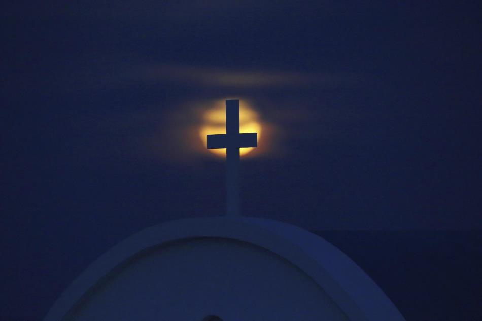 La superluna se levanta detrás de la cruz de la iglesia “Ayious Saranta” en Chipre.
