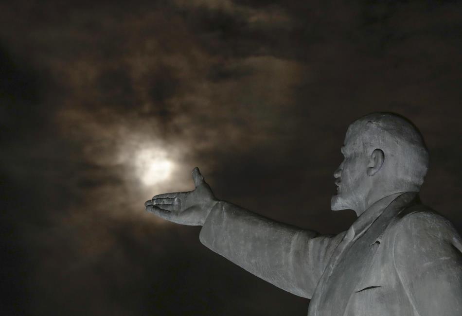 La superluna se levanta entre las nubes frente a la estatua de Vladimir Lenin en Kazakhstan.