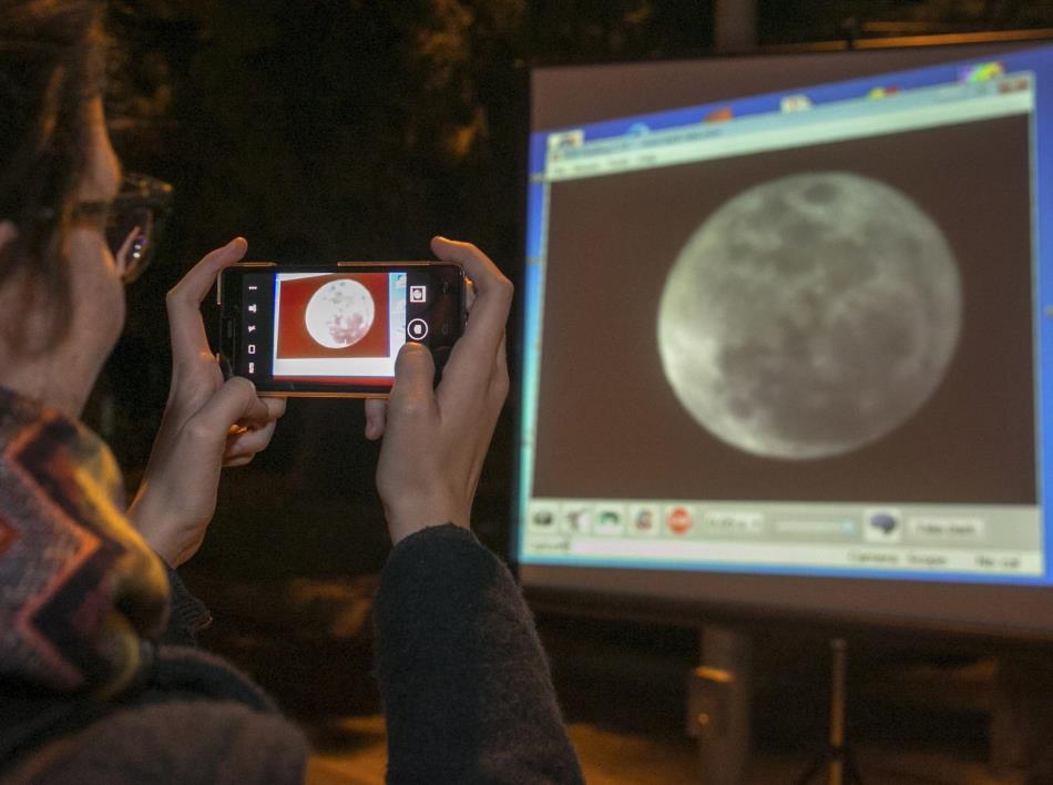 Una joven fotografía con su móvil la imagen de la luna proyectada por uno de los cuatro telescopios que la Universidad de Zaragoza ha instalado a las puertas de la Facultad de Ciencias de Zaragoza.
