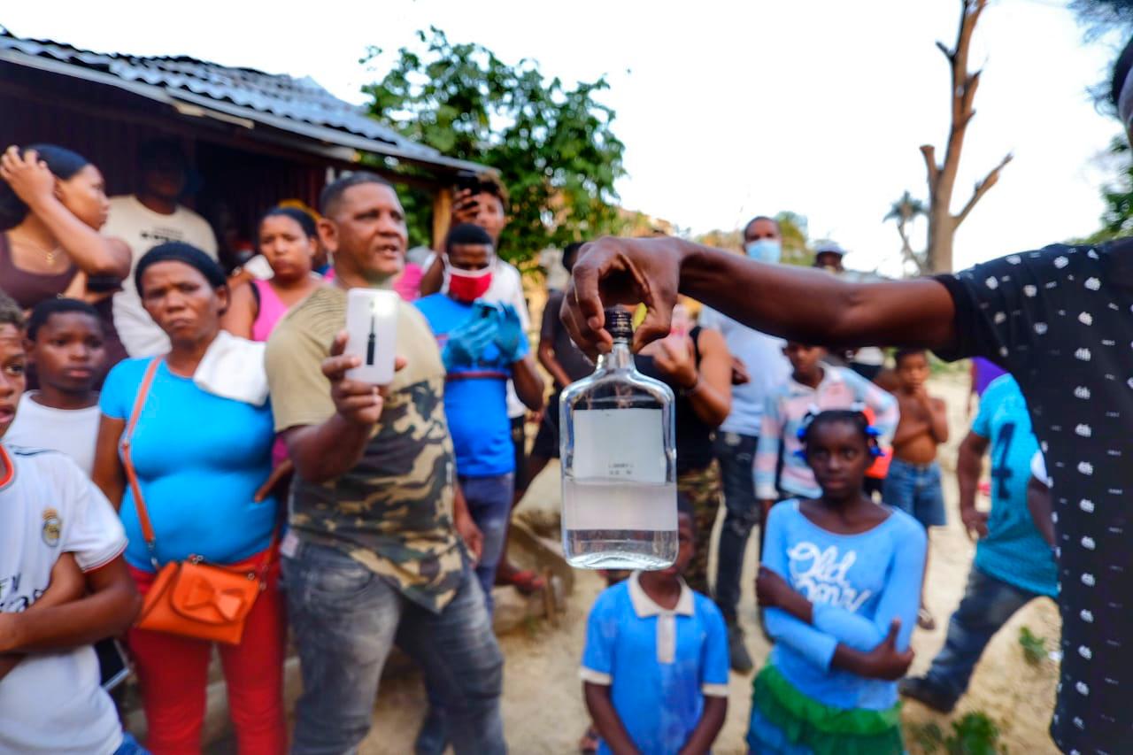 Personas del vecindario muestran la botella en la que compraron la bebida clandestina llamada popularmente “tapa floja”.