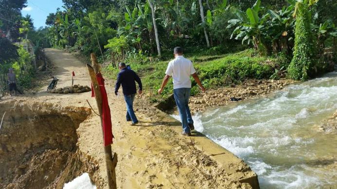 Dos hombres pasan por un derrumbe provocado por un afluente en Blanco al Medio, en la provincia Hermanas Mirabal
