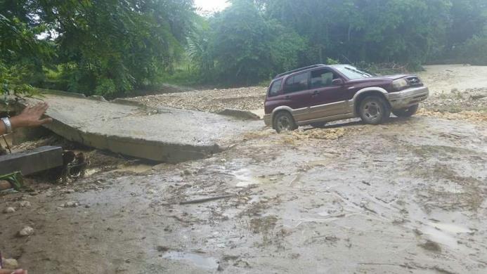 Un vehículo pasa por un puente afectado en Blanco al Medio, en la provincia Hermanas Mirabal