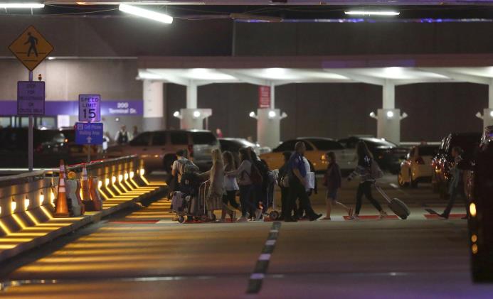 Los empleados y los pasajeros entran en el estacionamiento cerca de la escena de un tiroteo mortal en el aeropuerto internacional de Fort Lauderdale-Hollywood, el viernes 6 de enero de 2017, en Fort Lauderdale, Fla.
