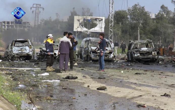 En la imagen tomada de un video proporcionado por la Agencia de Noticias Thiqa, rebeldes armados se encuentran en el lugar donde se registró una explosión que causó daños a varios autobuses y camionetas en el áreea de Rashideen.