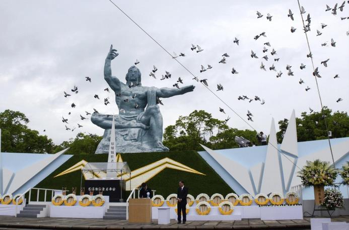Fotografía cedida que muestra a palomas sobrevolando la estatua de la Paz con motivo de la ceremonia conmemorativa en el Parque de la Paz Nagasaki.