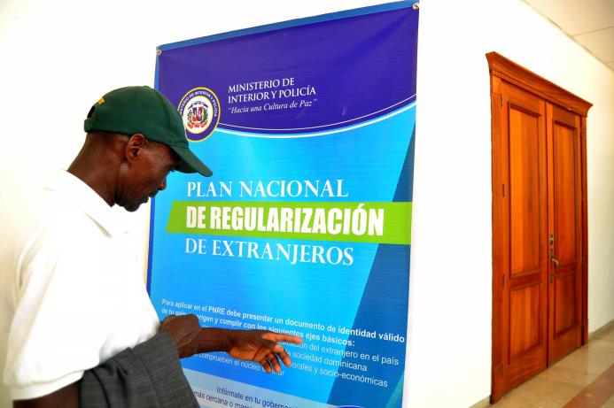 Imagen del 9 de junio de 2014 en la que se observa a un haitiano frente a un letrero del Plan Nacional de Regularización de Extranjeros, en la Gobernación de Santiago. 