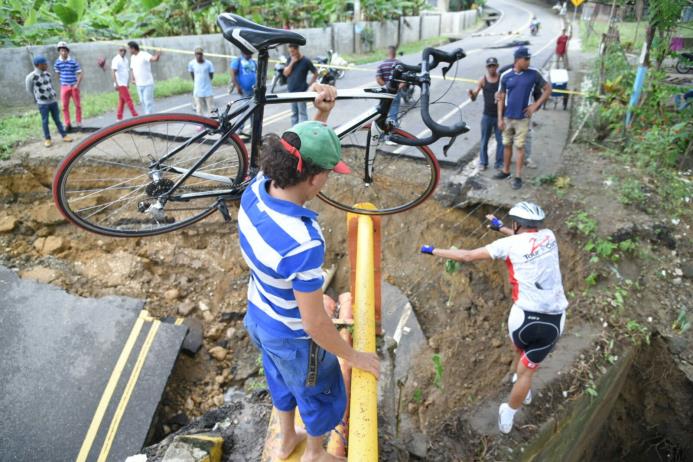 Ciclistas intentan cruzar a pie por el puente El Cacique, en Moca, que se derrumbó