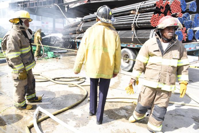 Bomberos mientras intentaban apagar el incendio el jueves pasado provocado por una patana en una estación de combustible en Santo Domingo Oeste.