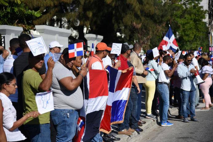 Personas en las cercanías del Congreso, mostrando la Bandera Nacional. 